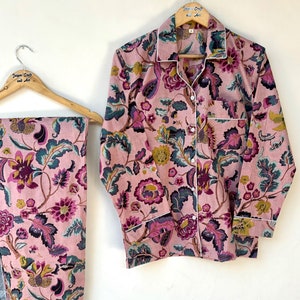 Puede incluir: Un conjunto de pijama rosa con estampado floral. La parte superior tiene mangas largas y un cierre de botones en la parte delantera. Los pantalones tienen una pierna recta.