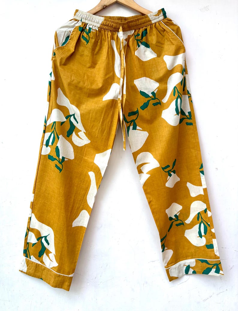 Puede incluir: Pantal&oacute;n amarillo mostaza con estampado floral blanco y verde. El pantal&oacute;n tiene una cintura el&aacute;stica y un cord&oacute;n.