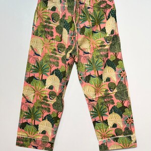 May include: Pink pajama pants with a green, white, and blue print of peacocks, trees, and buildings.
