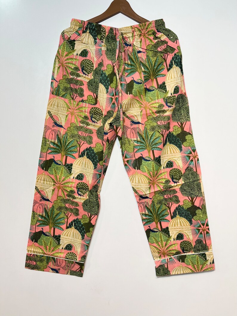 May include: Pink pajama pants with a green, white, and blue print of peacocks, trees, and buildings.