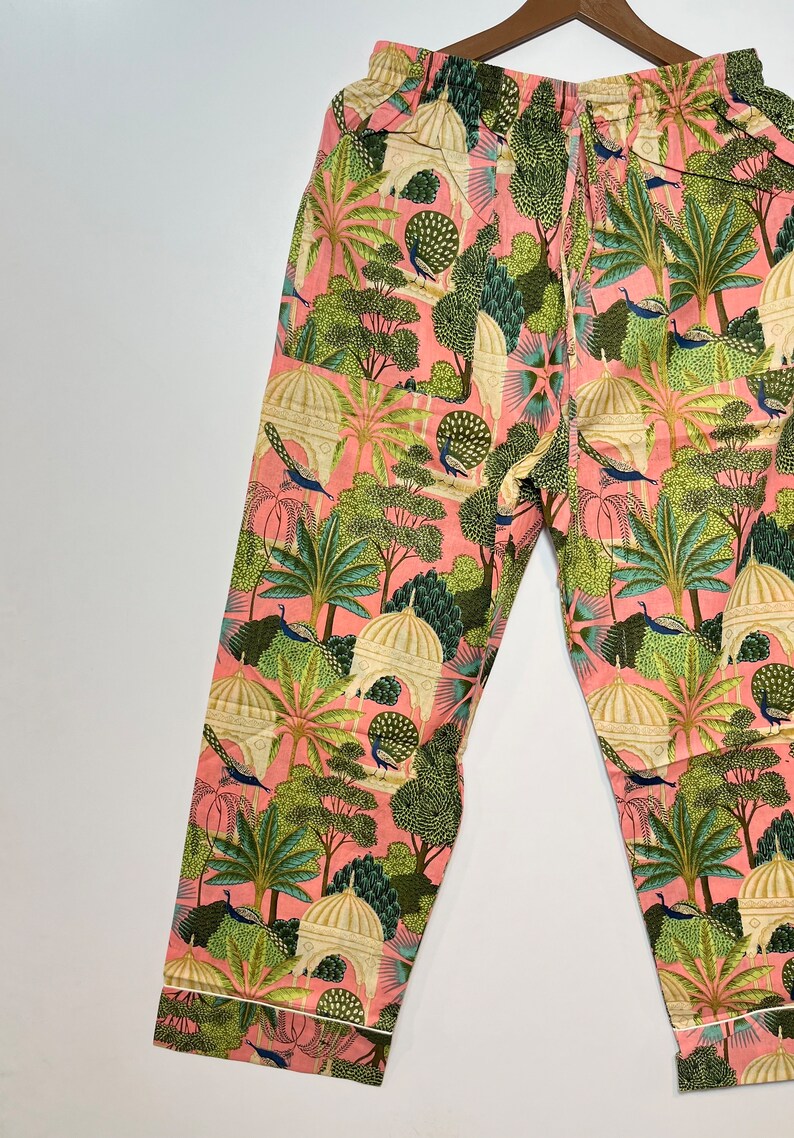 May include: Pink pajama pants with a white and green print of peacocks, trees, and buildings.