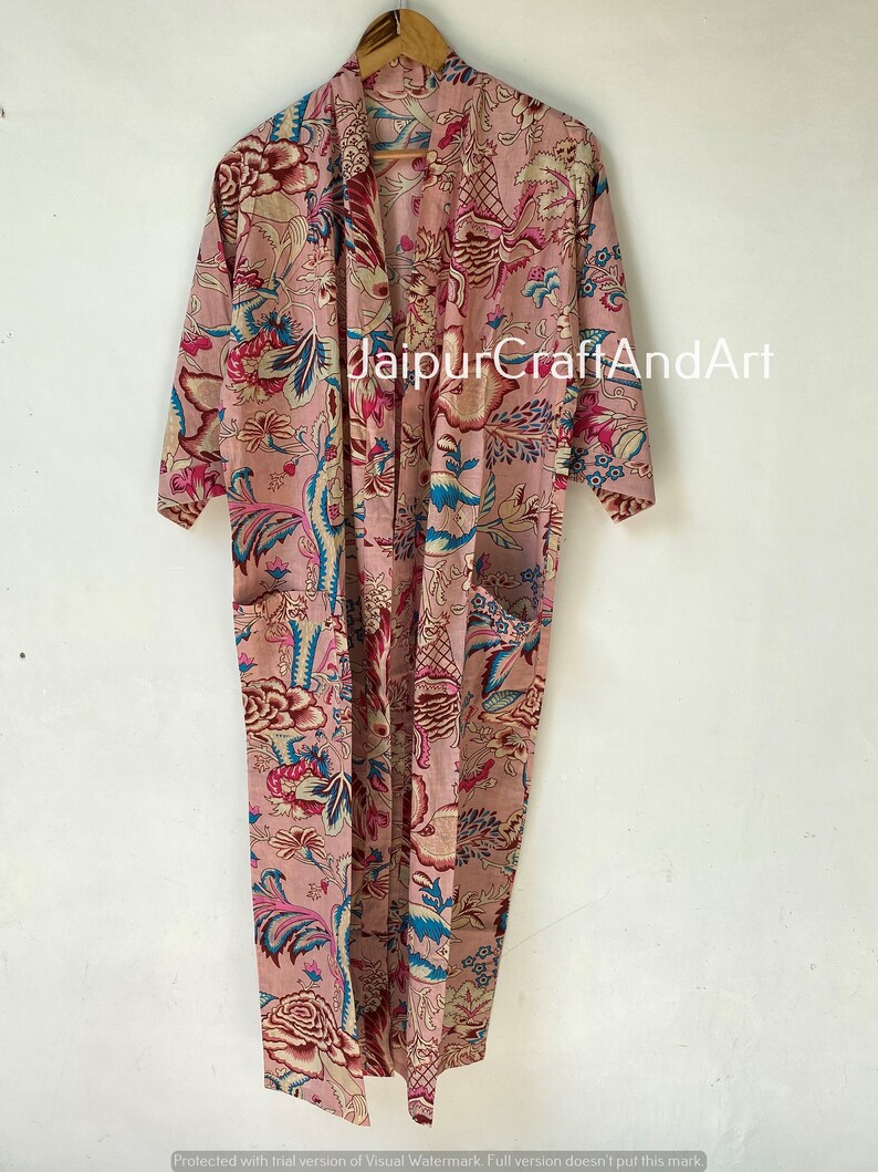 Pu&ograve; includere: Una lunga vestaglia di cotone rosa con stampa floreale in tonalit&agrave; di blu, rosso e bianco. La vestaglia ha un collo a scialle e una cintura da legare. Il testo "JaipurCraftAndArt" &egrave; stampato sulla vestaglia.