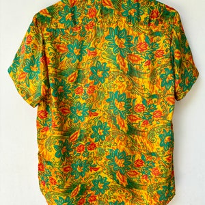 May include: A yellow short-sleeved shirt with a green and orange floral pattern.