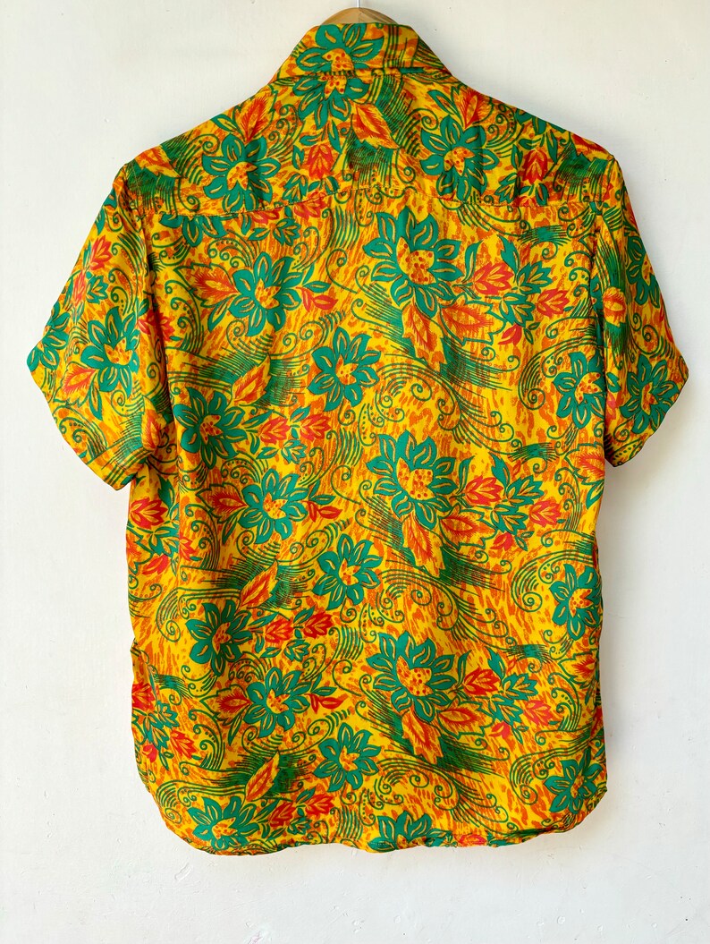 May include: A yellow short-sleeved shirt with a green and orange floral pattern.