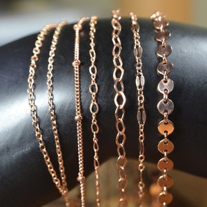 Puede incluir: Primer plano de varias pulseras de cadena de oro rosa delicadas con varios diseños de eslabones. Las pulseras se muestran sobre un fondo oscuro, mostrando sus intrincados patrones y su cálido color metálico. Se muestra una variedad de estilos.