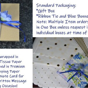 May include: A brown gift box tied with a blue ribbon and adorned with a blue flower. The box is wrapped in gold embossed tissue paper and premium delphinium wrapping paper. The image also shows a 2x2 hand-cut note card.