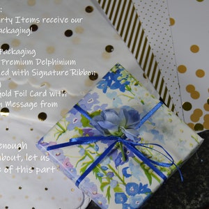 Puede incluir: Un regalo envuelto en papel floral con una cinta azul y un adorno floral. El embalaje incluye envoltorio individual, papel de primera calidad, una ramita floral y una tarjeta manuscrita. Se ve papel adicional con dise&ntilde;os.