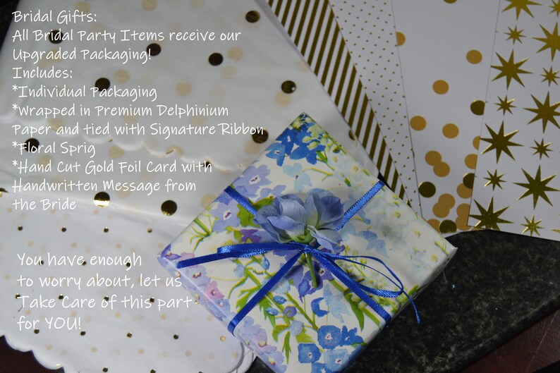 Puede incluir: Un regalo envuelto en papel floral con una cinta azul y un adorno floral. El embalaje incluye envoltorio individual, papel de primera calidad, una ramita floral y una tarjeta manuscrita. Se ve papel adicional con dise&ntilde;os.