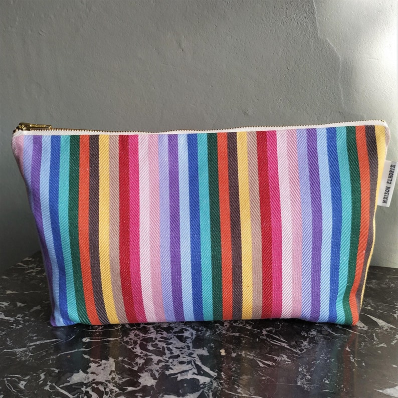 Large rainbow wash bag standing and zipped up on a black marble top