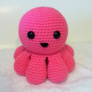May include: A pink crocheted octopus with black eyes and a black smile.