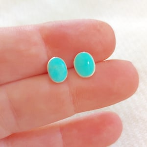 Peut inclure: Une paire de boucles d'oreilles ovales en turquoise avec des tiges en argent. Les boucles d'oreilles sont de couleur bleu clair.