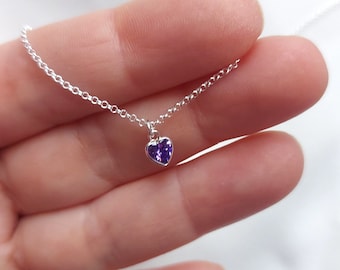 May include: A silver chain necklace with a small purple heart pendant.