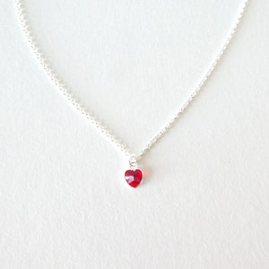 May include: A silver chain necklace with a small red heart pendant.