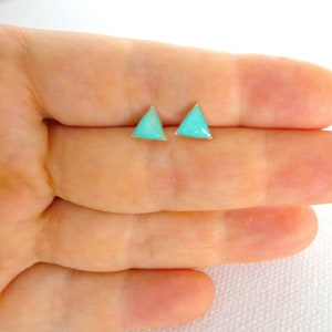 May include: A pair of silver triangle stud earrings with turquoise stones.