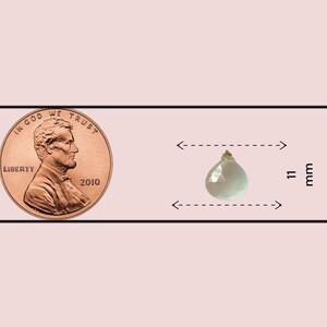 May include: A light green teardrop-shaped gemstone pendant with a gold bail. The pendant is 11 mm wide and 19.5 mm tall, as shown next to a US penny for size comparison.