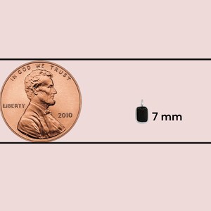 May include: A comparison of sizes between a US penny and a small black rectangular pendant. The penny is 19.5 mm in diameter and the pendant is 7 mm wide.