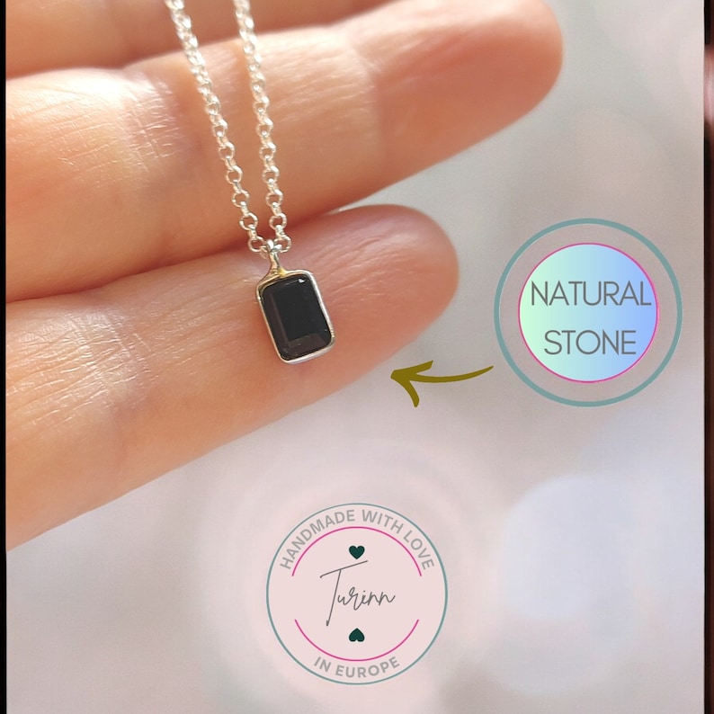 May include: A silver chain necklace with a small rectangular black gemstone pendant. The pendant is set in a silver bezel. The necklace is handmade with love in Europe. The image also includes the text "NATURAL STONE" and "HANDMADE WITH LOVE Turin IN EUROPE".