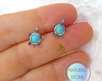 Puede incluir: Un par de pendientes de plata con forma de tortuga con piedras turquesa. Los pendientes son pequeños y delicados, y serían un gran regalo para alguien que ama las tortues.