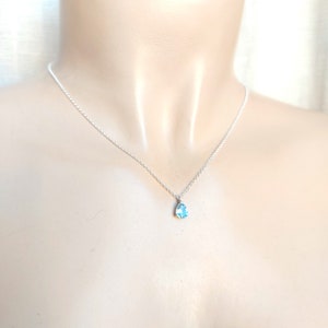 May include: A silver chain necklace with a teardrop-shaped blue gemstone pendant.