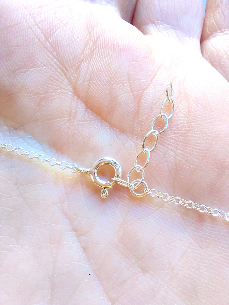 May include: Close-up of a silver chain necklace clasp with a lobster claw closure.