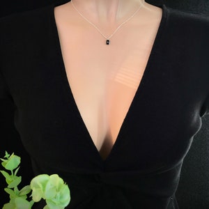 May include: A silver chain necklace with a small black rectangular pendant.