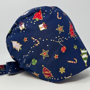 May include: Navy blue scrub cap with a festive Christmas pattern. It features red and white Christmas trees, gold stars, candy canes, and gift boxes. The design is set against a dark blue background.