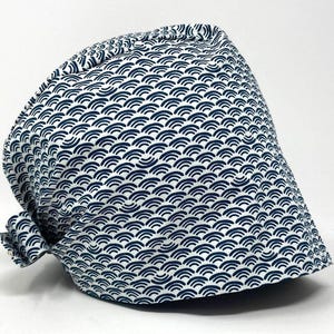Könnte beinhalten: Eine weiß-marineblaue gemusterte Kappe. Die Kappe hat ein sich wiederholendes wellenartiges Design in Marineblau auf weißem Hintergrund. Die Kappe ist hinten mit einer kleinen Schleife gebunden.