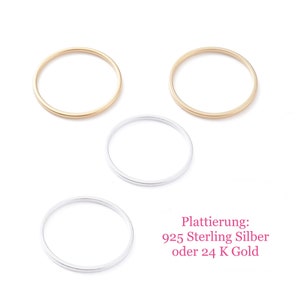 Könnte beinhalten: Drei schlichte, dünne Ringe aus Gold und Silber. Die Ringe sind auf einem weißen Hintergrund gestapelt. Plattierung: 925 Sterling Silber oder 24 K Gold.