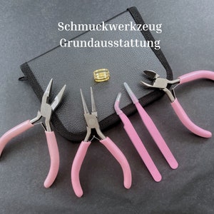 Könnte beinhalten: Ein Schmuck-Bastelset mit rosa-griffigen Werkzeugen, darunter Zangen und Pinzetten, angeordnet um einen goldenen Ring und eine schwarze Tasche. Der Text "Schmuckwerkzeug Grundausstattung" ist sichtbar.