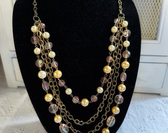 May include: A multi-strand necklace with gold chains and iridescent pink and cream beads.