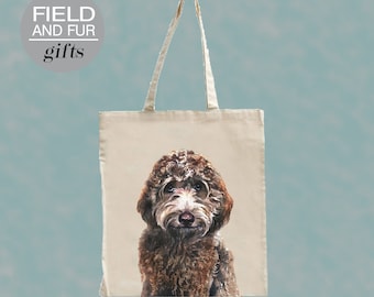 May include: A brown and white doodle dog is printed on a beige tote bag. The bag has black handles and the text "FIELD AND FUR gifts" is printed on a gray circle in the top left corner.