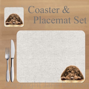 Peut inclure: Un ensemble de dessous-de-verre et un set de table en tissu brun et blanc représentant un chien brun avec la tête reposant sur ses pattes. Le texte "Coaster & Placemat Set" est imprimé en gris en haut de l'image.