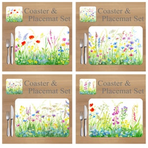 Op de afbeelding: Set van vier witte keramische onderzetters en bijpassende placemats met een aquarel-illustratie van een veld vol wilde bloemen in tinten roze, paars, blauw, geel en groen. De tekst "Coaster & Placemat Set" is in grijs op elk stuk gedrukt.