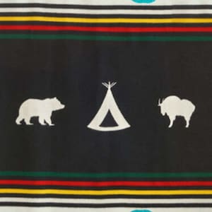 May include: A black and white patterned fabric with a teal blue border. The fabric features a white silhouette of a bear, a tent, and a mountain goat. The fabric has a repeating pattern of red, yellow, and green stripes.
