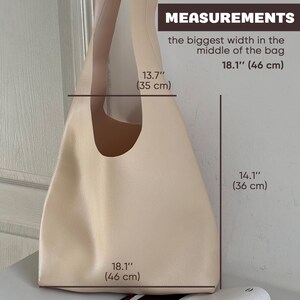 May include: A beige leather tote bag with measurements in inches and centimeters. The bag is 18.1 inches (46 cm) wide at the bottom, 13.7 inches (35 cm) wide at the top, and 14.1 inches (36 cm) tall.