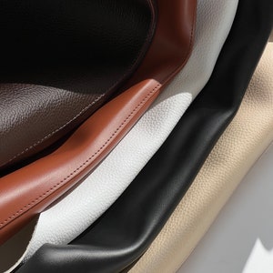 May include: Close-up of four different types of leather in brown, tan, white, and black. The leather is textured and has a soft, supple feel.