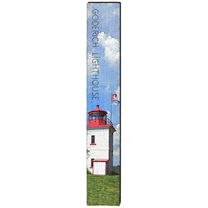 May include: A rectangular wooden sign featuring a painting of the Goderich Lighthouse. The lighthouse is white with a red top and sits on green grass under a blue sky with clouds. The text "Goderich Lighthouse" is printed vertically.