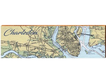 May include: A rectangular wooden sign featuring a printed nautical map of Charleston, South Carolina. The map displays land in tan, water in light blue, and black grid lines for streets. The word Charleston is written in blue script.