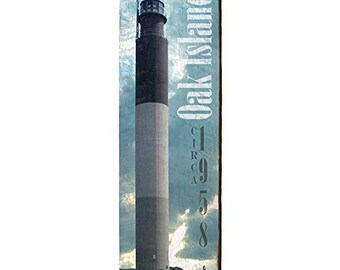 May include: A rectangular wooden sign featuring a tall lighthouse with black, white, and gray sections against a cloudy blue sky. The text "Oak Island" and "Circa 1958" are printed vertically on the right side.