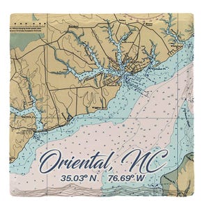 Könnte beinhalten: Ein quadratischer Steinuntersetzer mit einer Seekarte von Oriental, North Carolina. Die Karte zeigt beigefarbene Landmassen und hellblaues Wasser mit Tiefenangaben. Der Text lautet Oriental, NC und 35.03 N, 76.69 W in dunkelblauer Schrift.