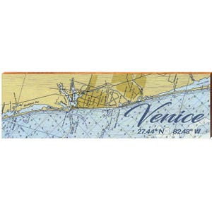 May include: A wooden nautical chart of Venice, Florida, with the city name in a cursive font. The chart features blue and yellow tones, with latitude and longitude coordinates. The wooden frame adds a rustic touch.