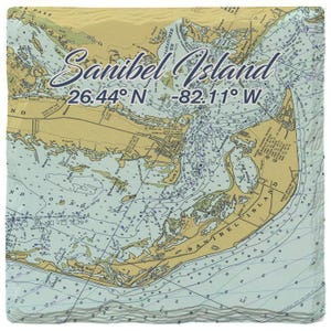 Könnte beinhalten: Ein quadratischer Steinuntersetzer mit einer Seekarte von Sanibel Island, die beigefarbene Landmassen und hellblaues Wasser zeigt. Der Text Sanibel Island und die Koordinaten 26,44° N -82,11° W sind dunkelblau in der Mitte aufgedruckt.