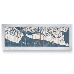 May include: A rectangular wall art piece featuring a map of Townsends Inlet, New Jersey, printed on vertical wooden planks with a distressed blue and white finish, enclosed in a weathered white wooden frame with a clean, horizontal orientation.