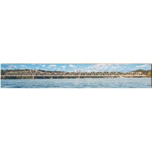 May include: A panoramic image of a bridge over water. The bridge has a white metal truss design. The sky is blue with clouds. The water is light blue. The image is printed on a wooden panel. The bridge is a prominent feature.
