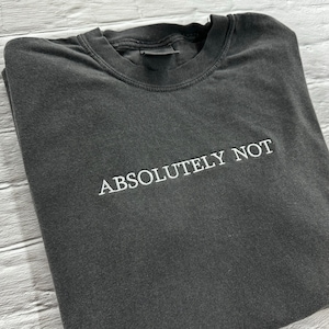 May include: A dark grey t-shirt with the text "ABSOLUTELY NOT" embroidered in white on the front.