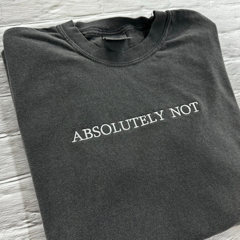 May include: A dark grey t-shirt with the text "ABSOLUTELY NOT" embroidered in white on the front.