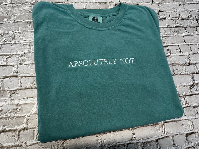 May include: A teal green t-shirt with the text "ABSOLUTELY NOT" embroidered in white.