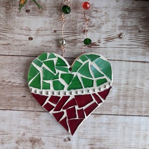 May include: A mosaic heart ornament with green and red glass pieces. The top half is green, the bottom red, separated by a row of silver studs. It hangs from copper wire with green and red beads, and silver beads.