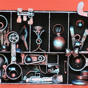 Peut inclure: Une boîte en métal noir avec une grille de compartiments remplis de divers petits objets en métal, notamment des engrenages, un nœud, une bouteille et une pince. Les objets sont peints dans des tons argent, cuivre et bleu.
