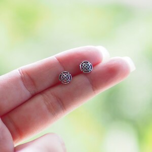 K&ouml;nnte beinhalten: Ein Paar silberne Ohrringe mit einem runden, filigranen Design. Die Ohrringe sind klein und zart.
